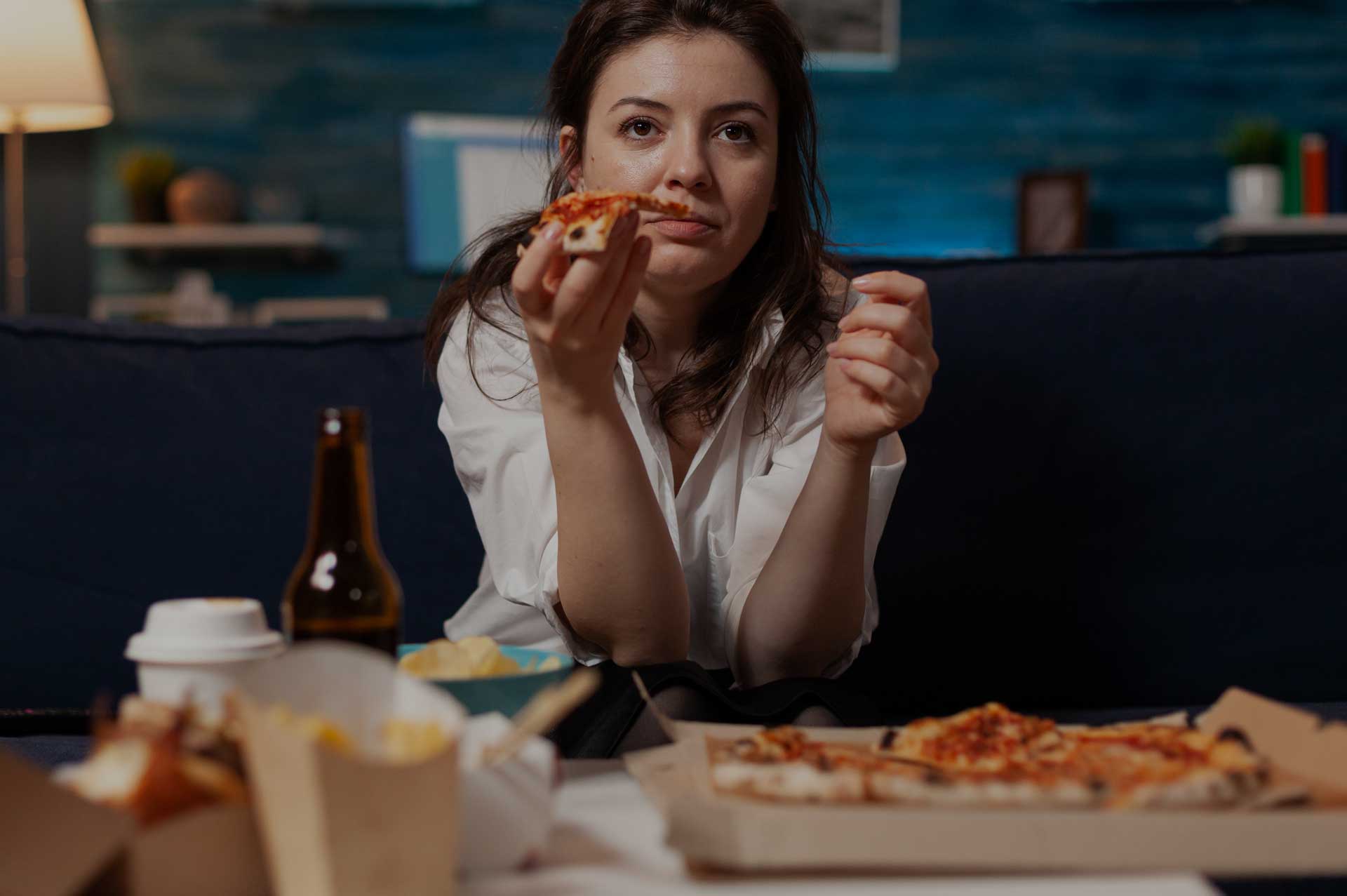 Future Search Trials Binge Eating Disorder (BED) Research study in Dallas, Texas. Woman eating unhealthy pizza and fast food while watching tv.